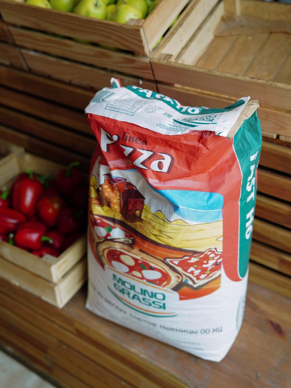 Close up of Molino Grassi flour bag next to crates of fresh vegetables.