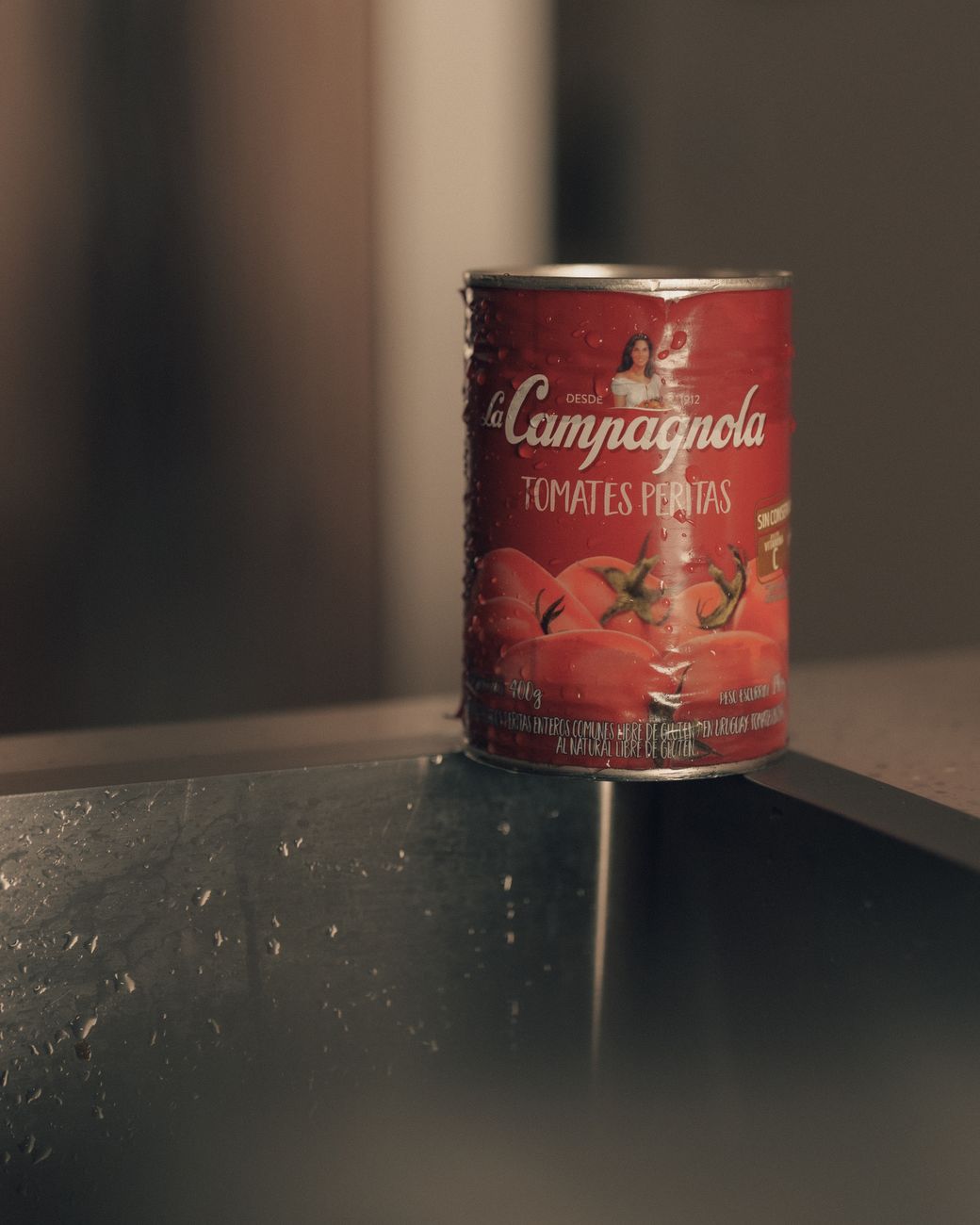 A can of La Campagnola tomatoes on a kitchen counter with soft lighting.