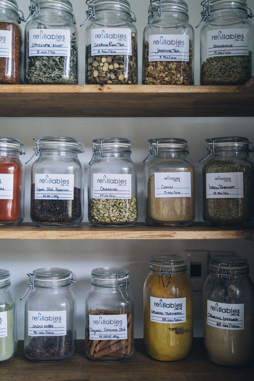 Organized glass jars filled with organic spices on wooden shelves showcasing eco friendly storage.