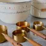 Stylish kitchen setup with vintage mixing bowls and gold measuring cups.
