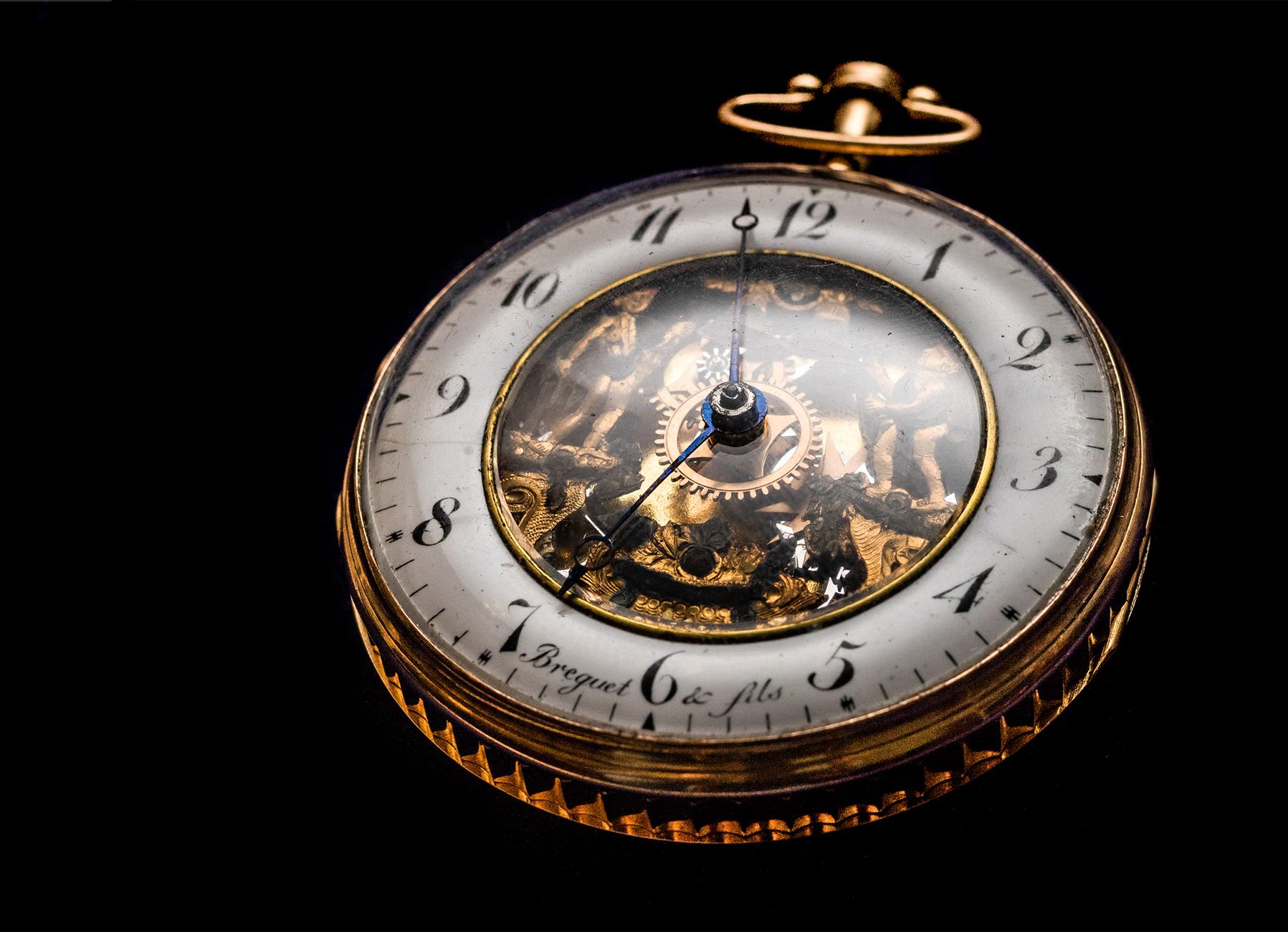 Close up of a vintage gold pocket watch showcasing intricate gears on a black backdrop.