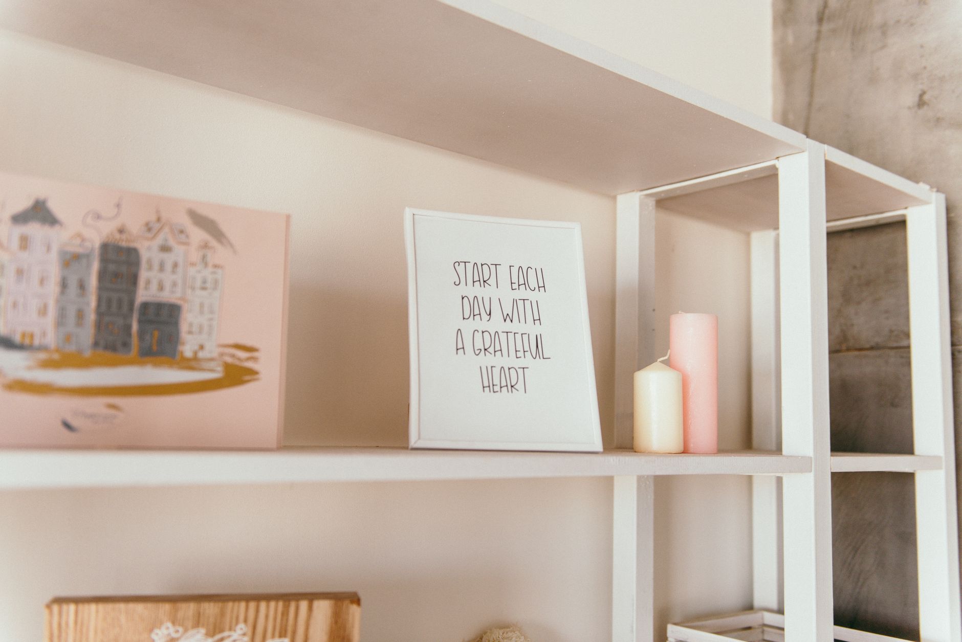 Stylish white shelf with candles and an inspirational quote frame for modern interior decoration.