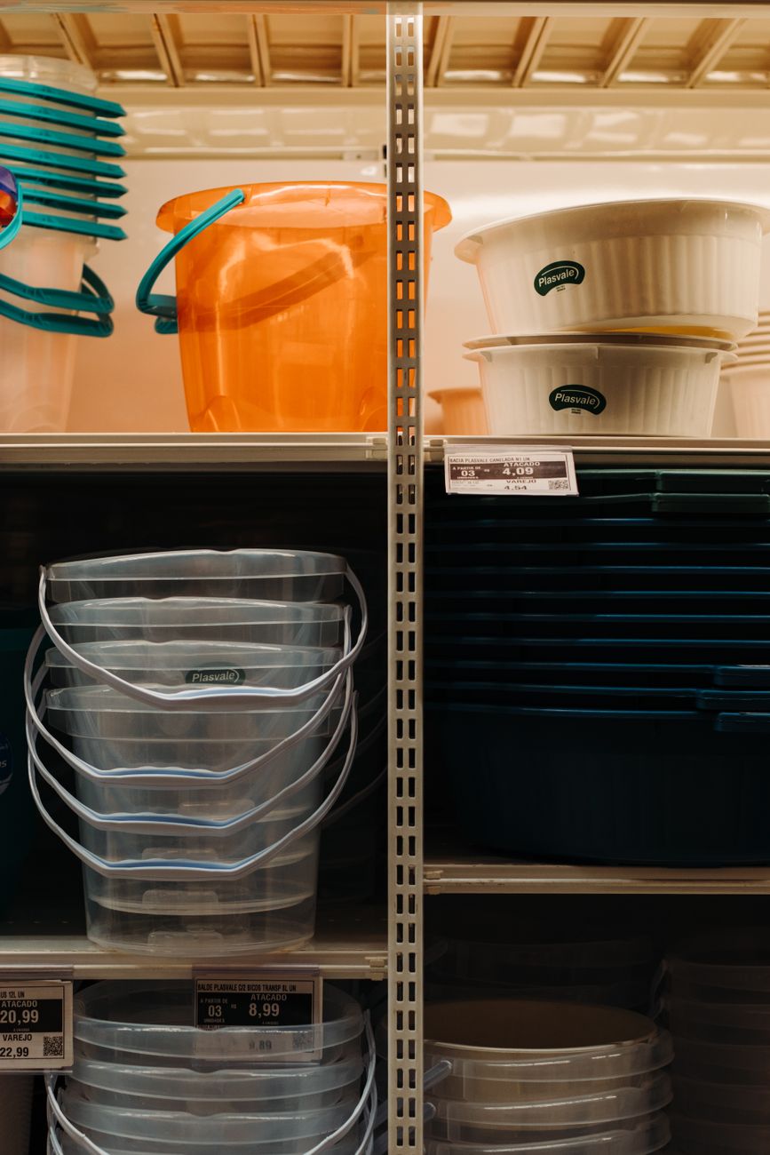 A vertical shot of plastic buckets and containers displayed on store shelves with visible price tags.