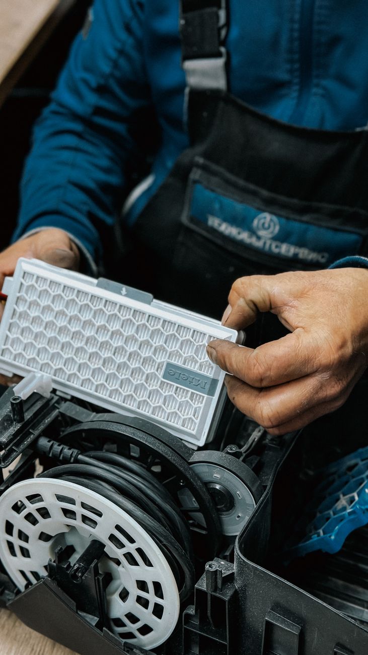 Close up of a technician handling an air filter during a vacuum cleaner repair.