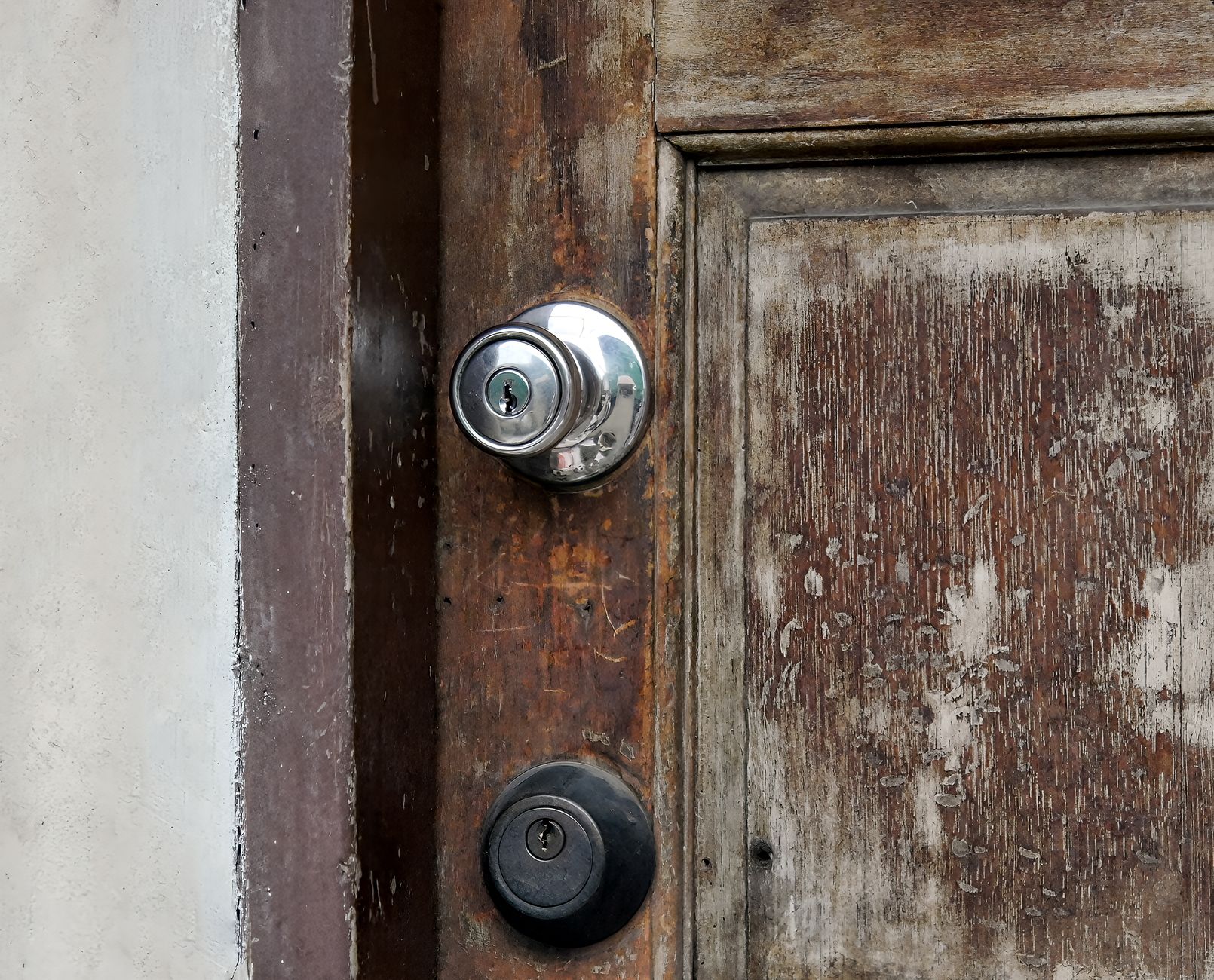 Close up of a weathered wooden door with metal locks, showcasing aged and rustic features.