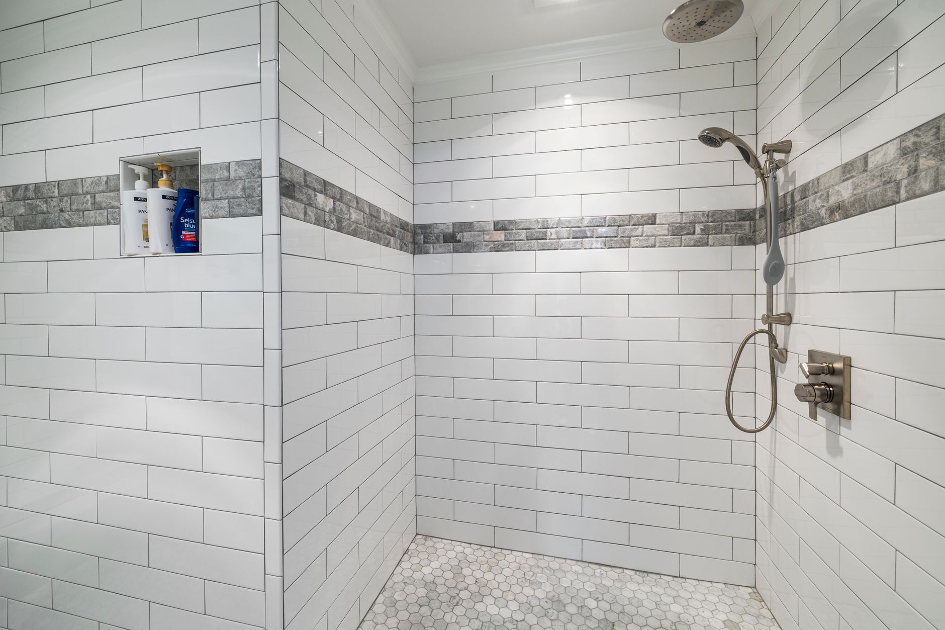 Spacious modern bathroom with white tiles and sleek shower design.