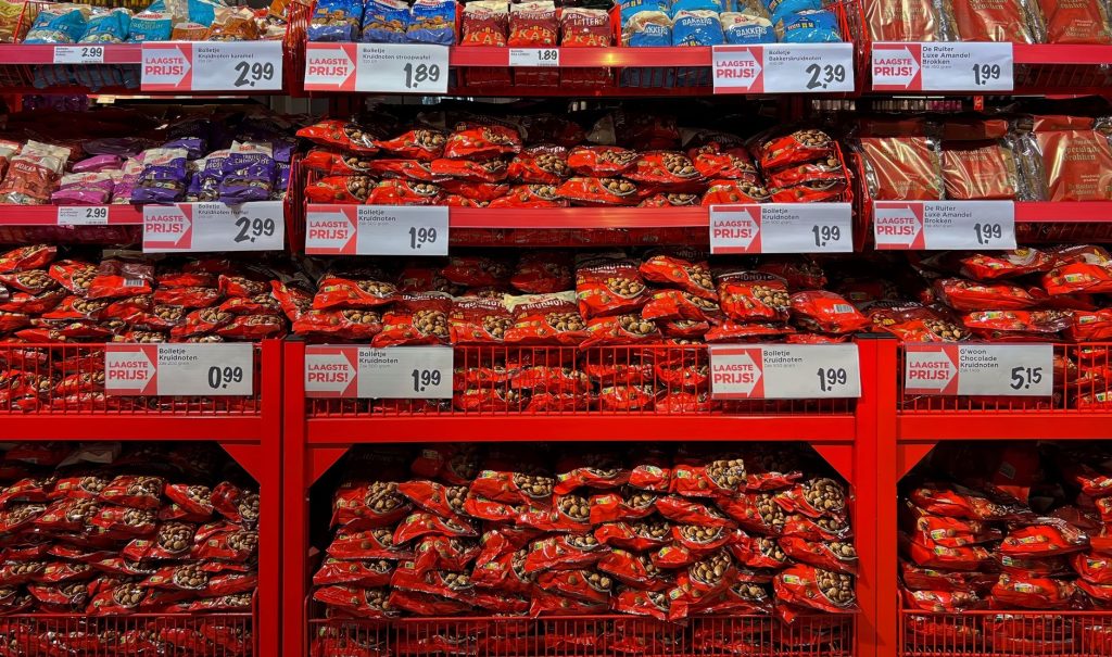 Vibrant assortment of candy bags in a supermarket with signs in Dutch promoting low prices.