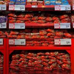 Vibrant assortment of candy bags in a supermarket with signs in Dutch promoting low prices.