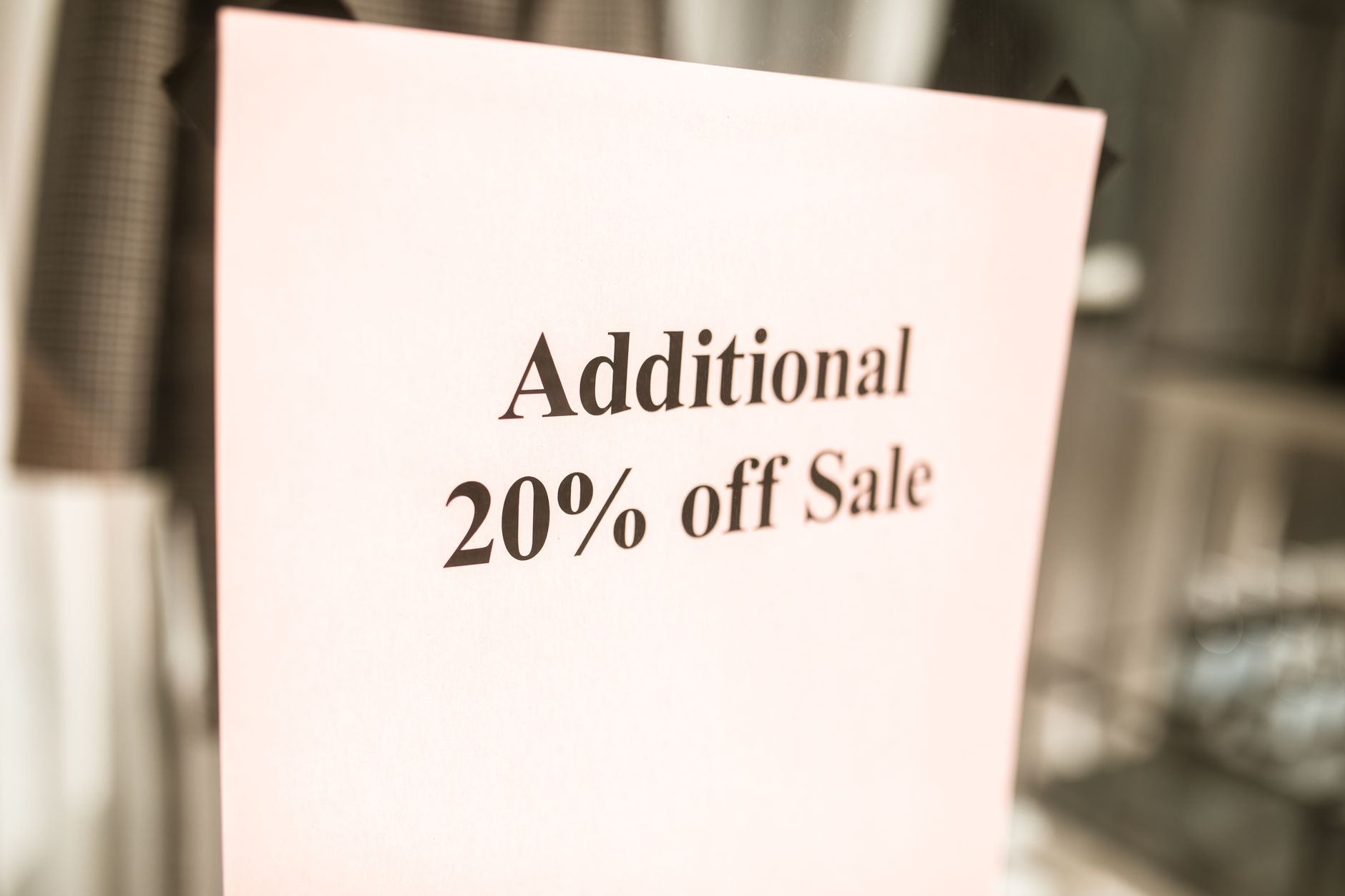 Close up of a sale sign offering an additional 20% discount in a store window.