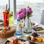 A luxurious dining table set with gourmet food and drinks overlooking a beautiful cityscape.