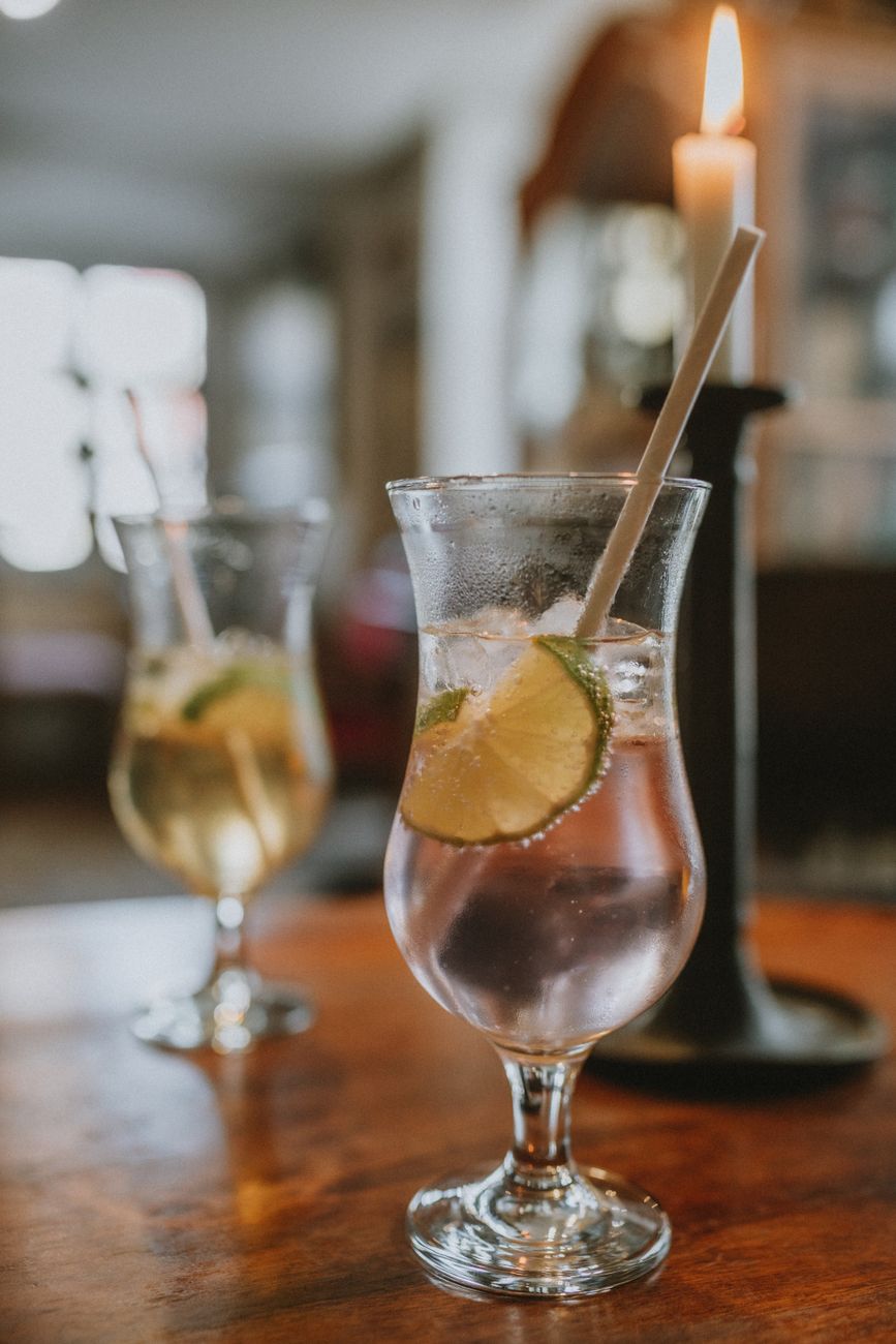 Elegant glasses of lime infused cocktails with ice on a wooden table, candle lit ambiance.