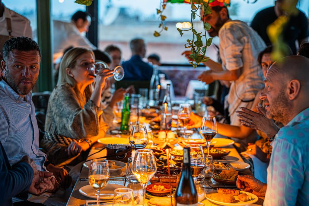 A lively gathering of friends enjoying a candlelit dinner with wine and conversation.