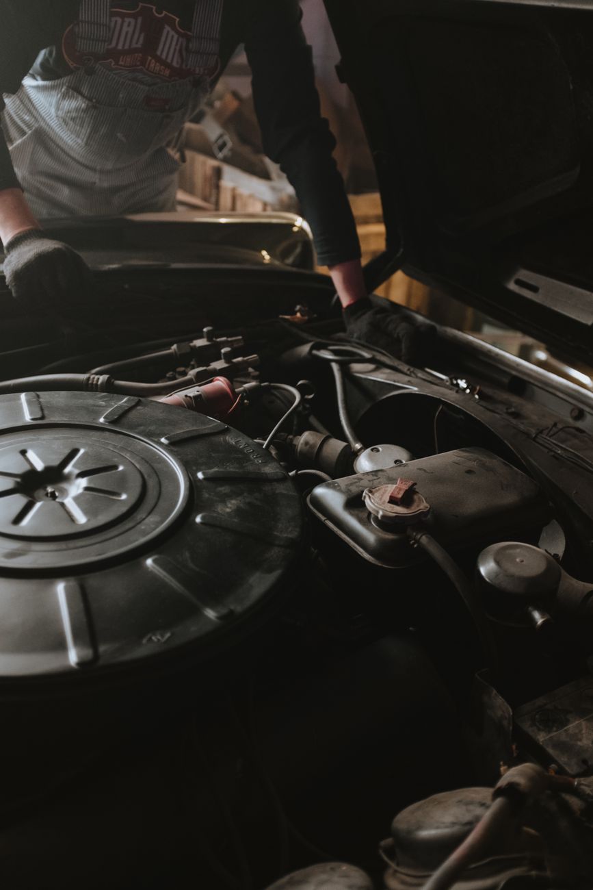Close up of a mechanic repairing a car engine in a garage setting.
