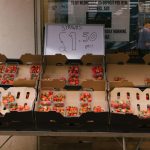 Plastic containers of strawberries for sale at a market stall, priced at £1.50 each.