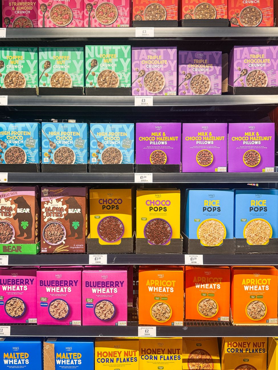 Vibrant cereal boxes on shelves in a Swindon, UK supermarket, showcasing a variety of flavors.