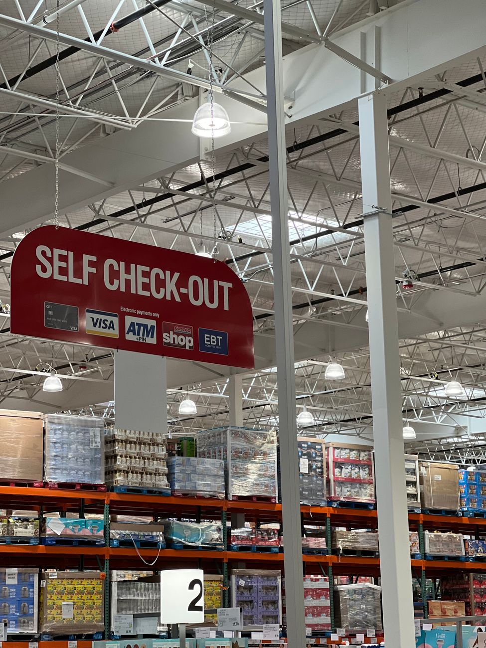 Self check out section in a large warehouse store with visible payment options.