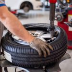 Close up of an auto mechanic changing a tire with precision equipment in a professional workshop.