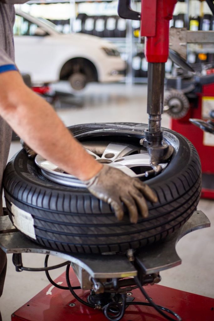 Close up of an auto mechanic changing a tire with precision equipment in a professional workshop.