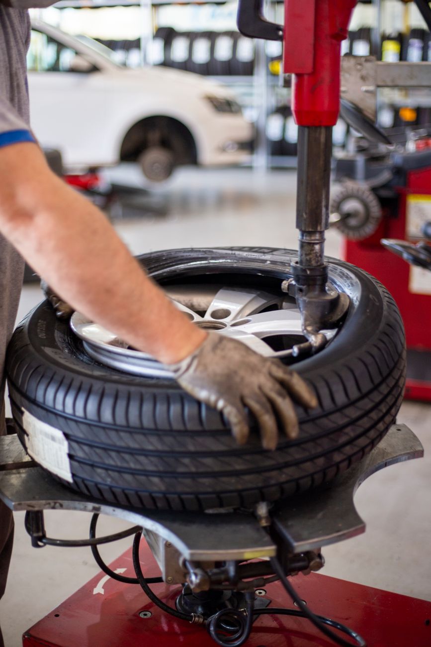 Close up of an auto mechanic changing a tire with precision equipment in a professional workshop.