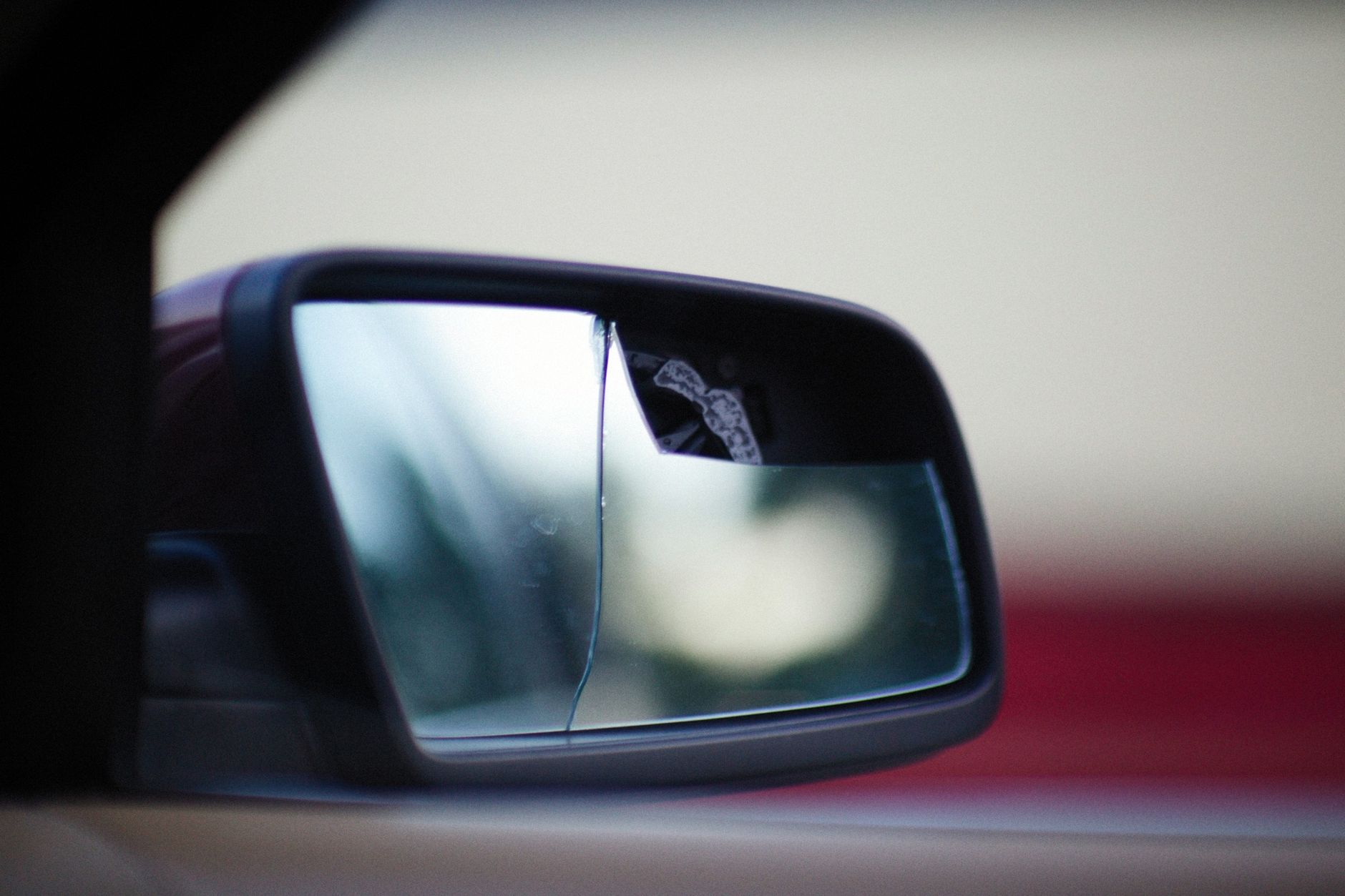 Detailed close up of a broken car side mirror reflecting abstract scenery.