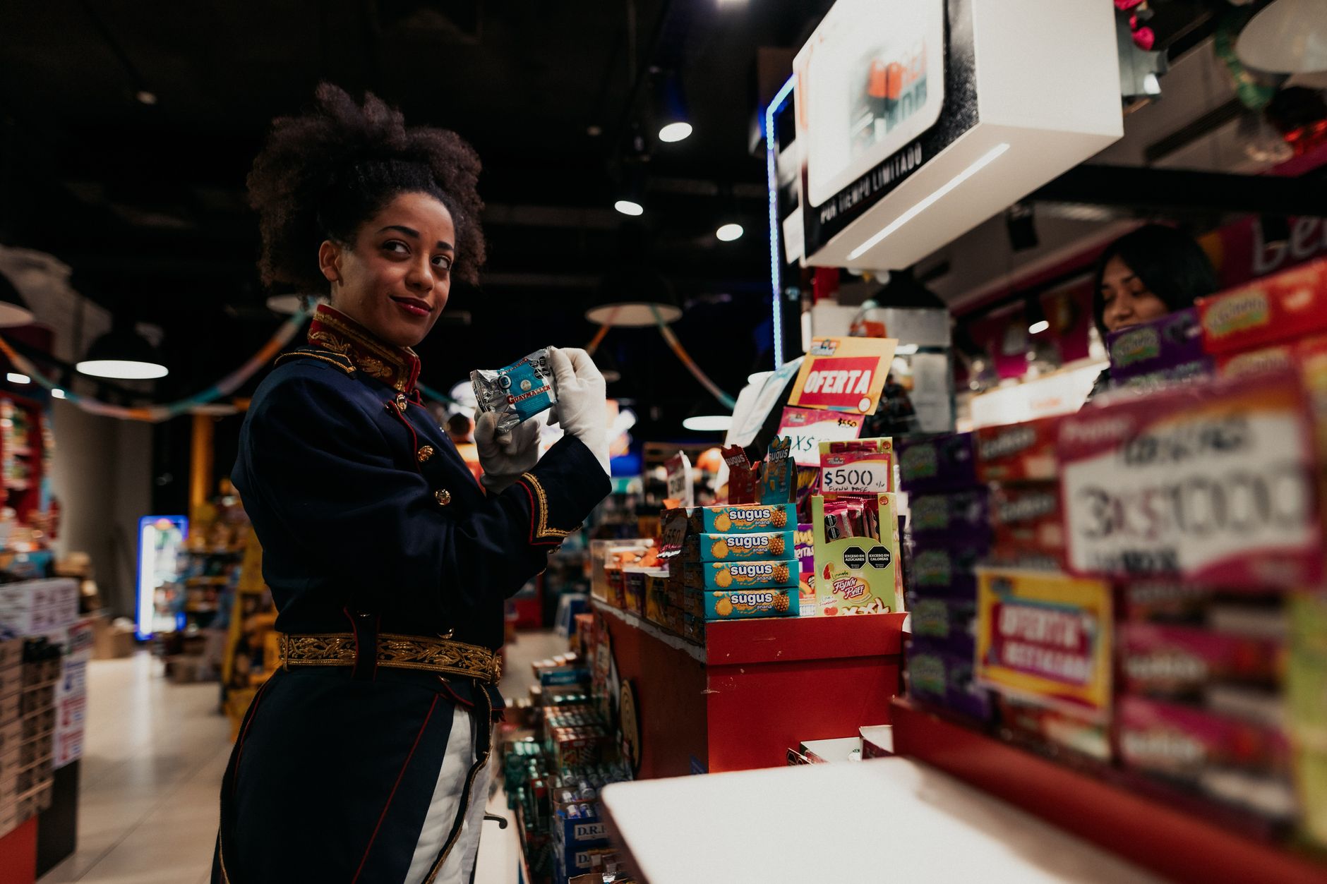 A woman in a uniform browses candy in a Buenos Aires store.