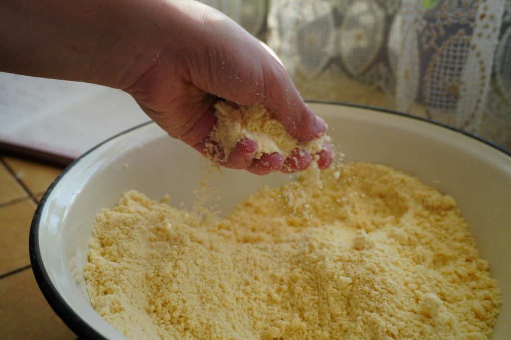 Hand sifting yellow flour into a bowl