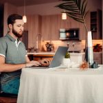 a person sitting at a table with a laptop