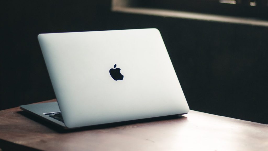 a white apple laptop sitting on top of a wooden table