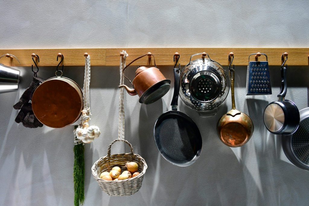 Various kitchen utensils hanging on a wooden rack.