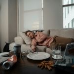 a woman laying on a couch with a plate of food