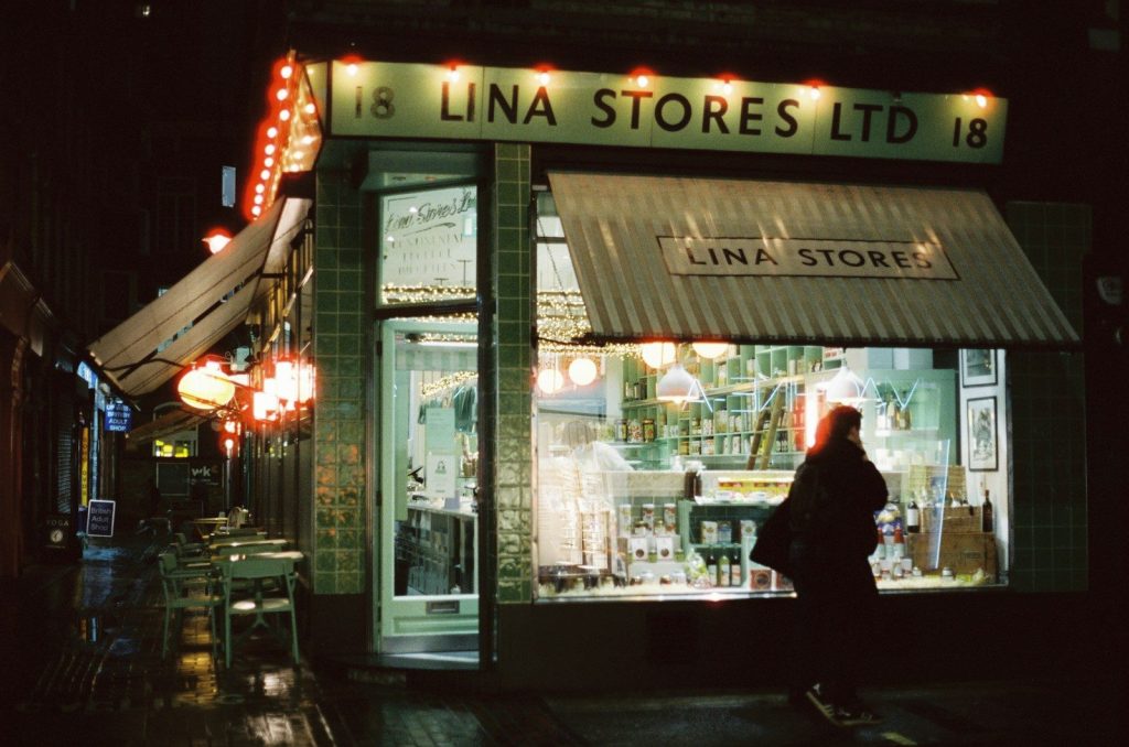 a woman walking past a store front at night
