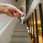 Here's a possible caption: keys being held in front of a staircase.