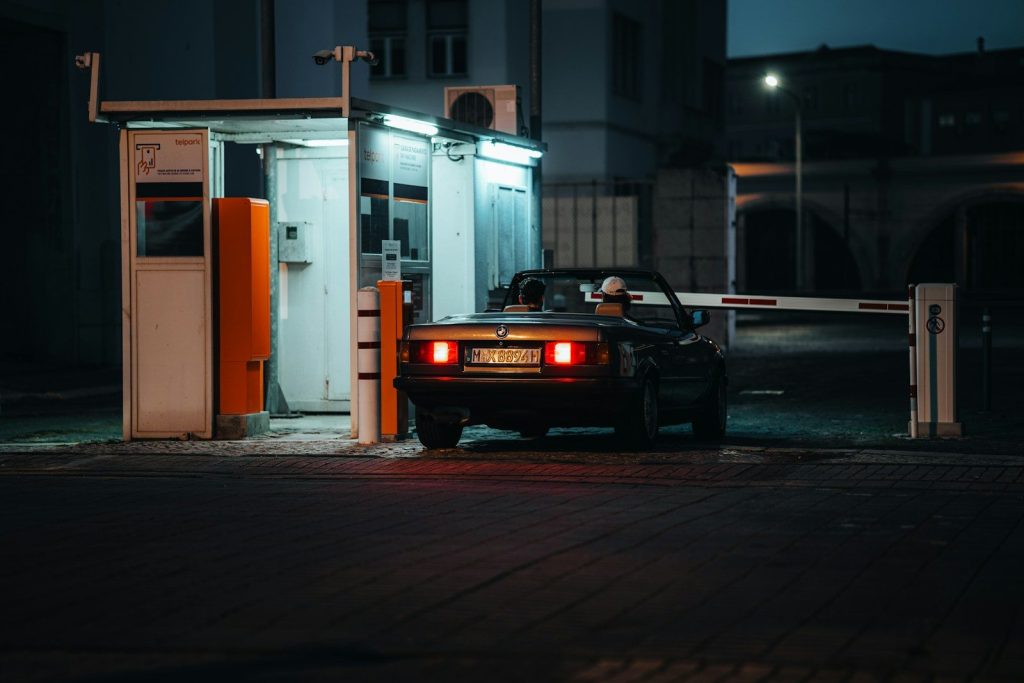 Car approaching a parking barrier at night.