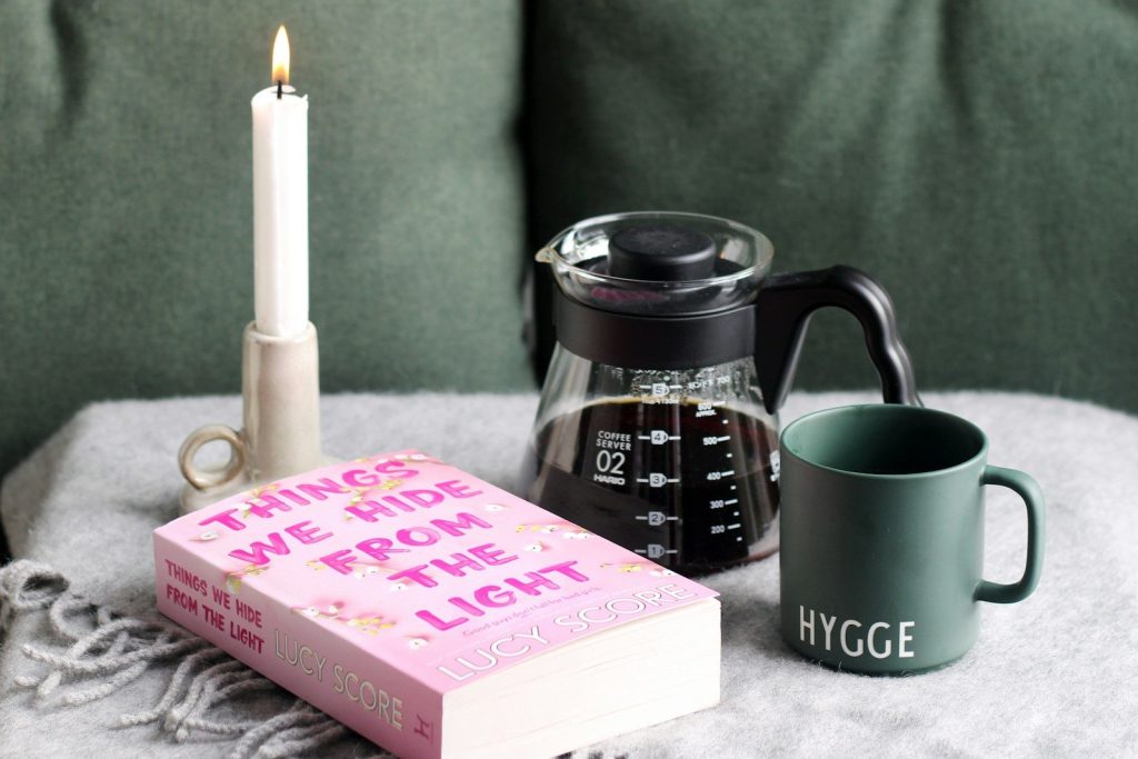 a coffee pot, a candle, and a book on a blanket
