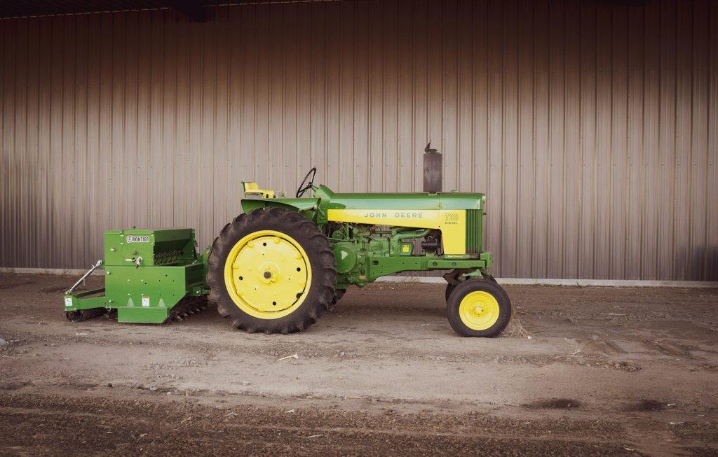 a green and yellow tractor parked in front of a building