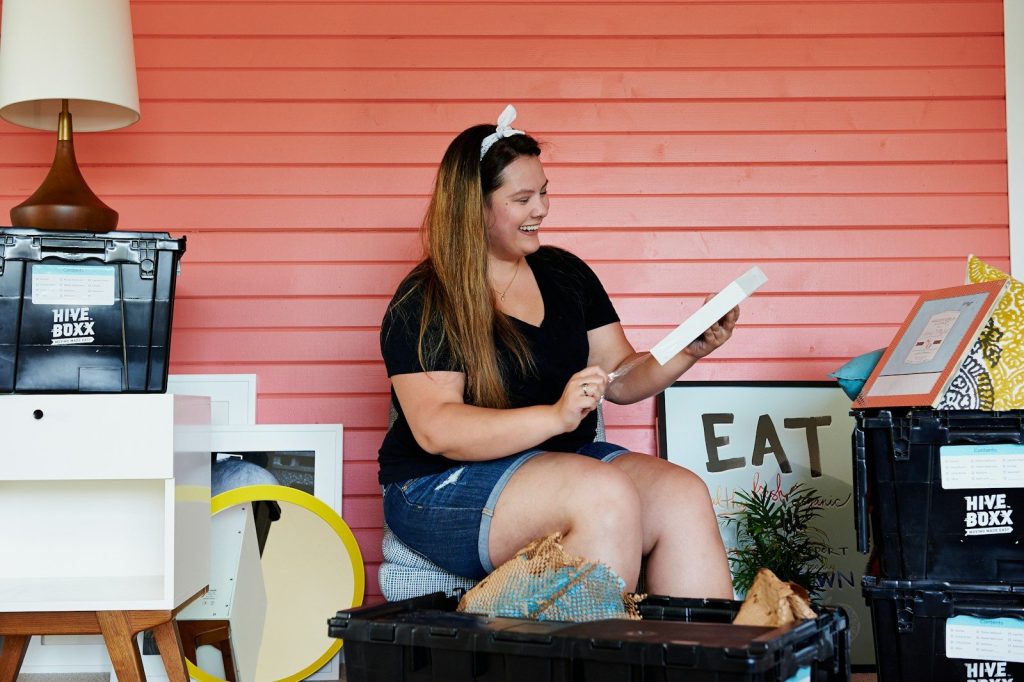 woman in black shirt and blue denim shorts sitting on brown woven basket