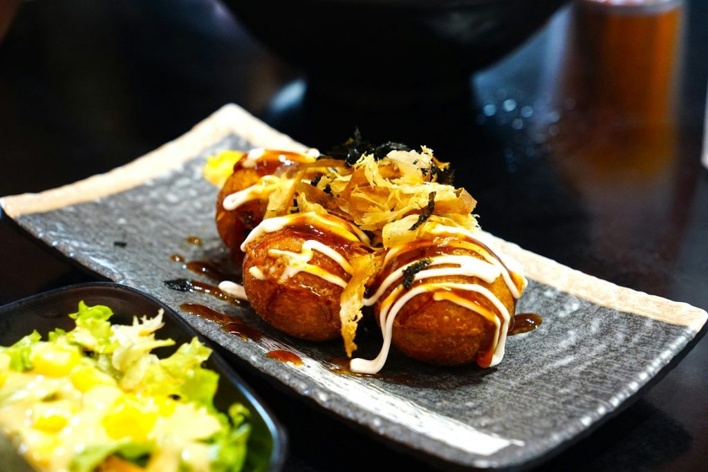 Takoyaki balls drizzled with sauce and toppings