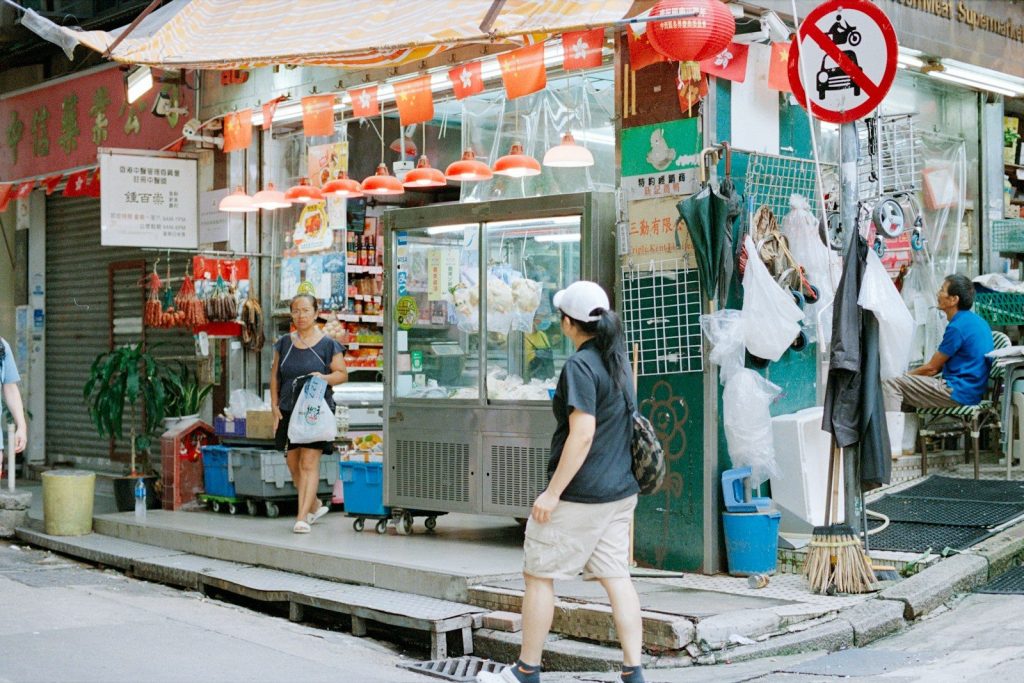 Street corner with a small shop and people walking.