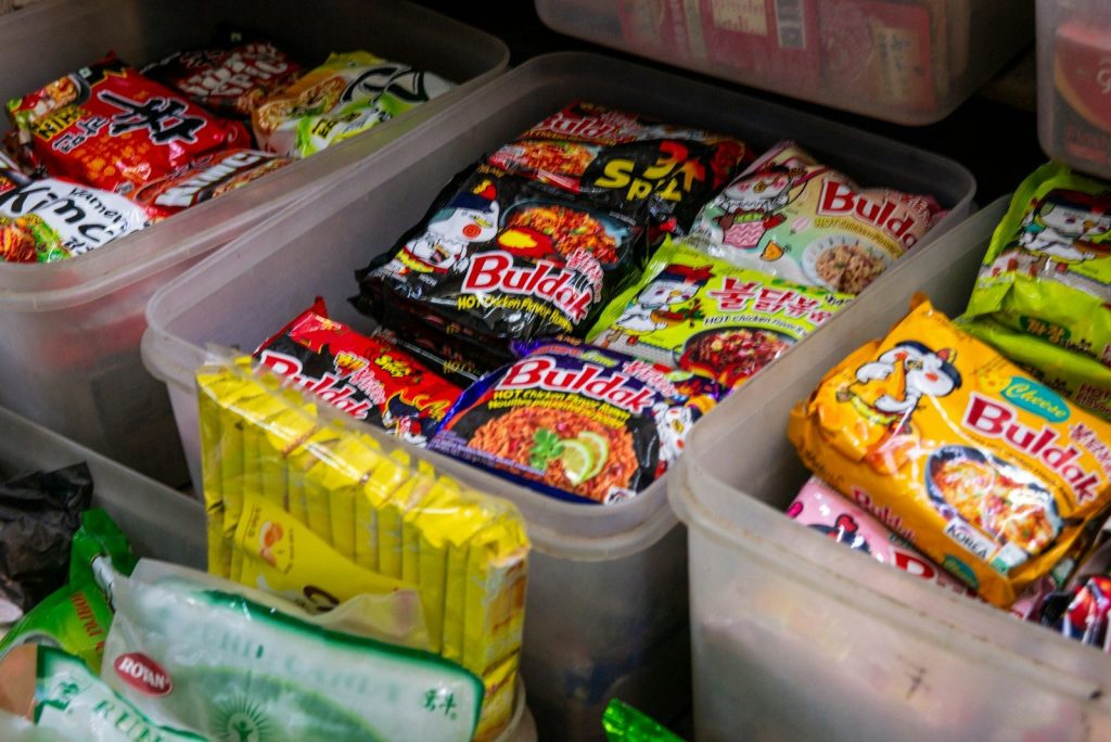Assorted instant noodle packets in plastic containers.