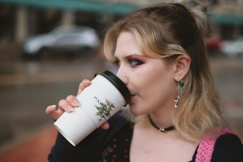 a woman drinking out of a coffee cup