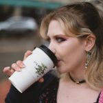 a woman drinking out of a coffee cup