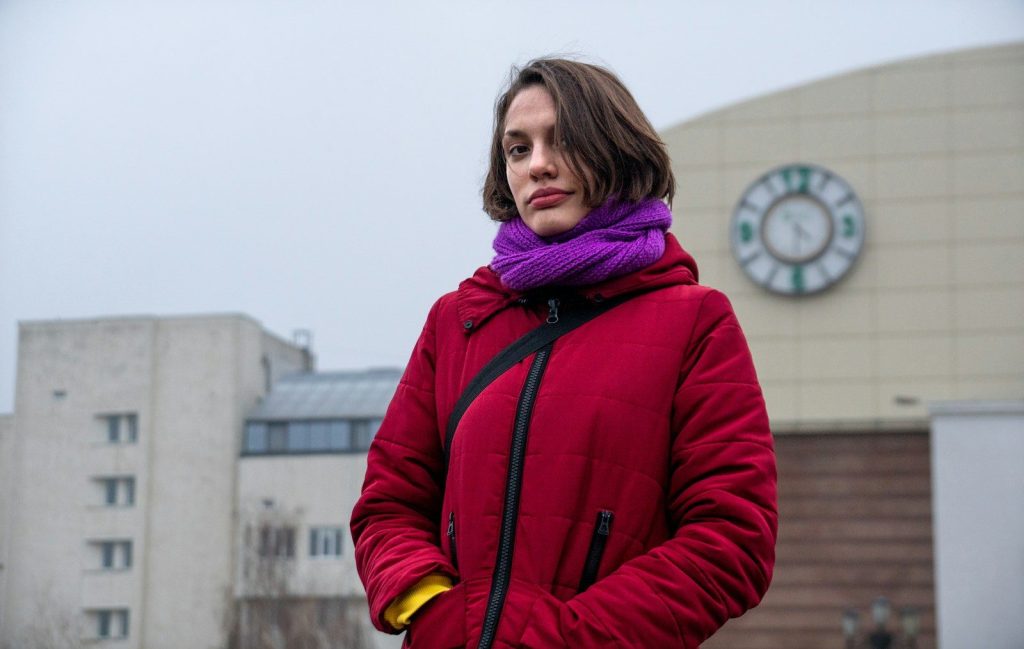 A woman standing in front of a building with a clock in the background