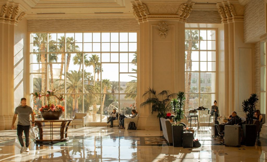 Opulent hotel lobby with sunlight and people relaxing.