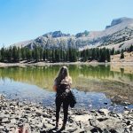 woman in black jacket standing on rocky shore during daytime