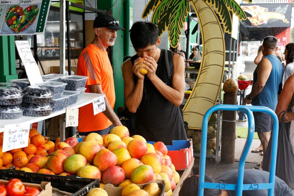 a couple of people standing around a fruit stand