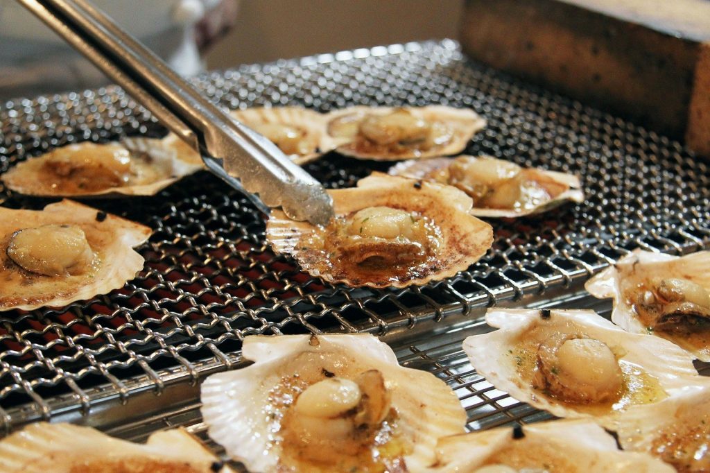 Scallops being grilled on a metal grate.