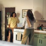 Two women talking in a kitchen while cooking