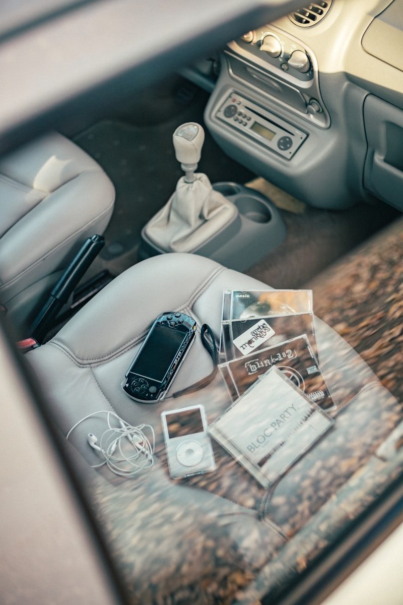 A psp, ipod, and cds on a car seat.