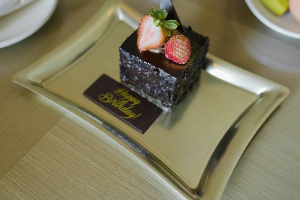 A slice of chocolate cake with strawberries and birthday message.