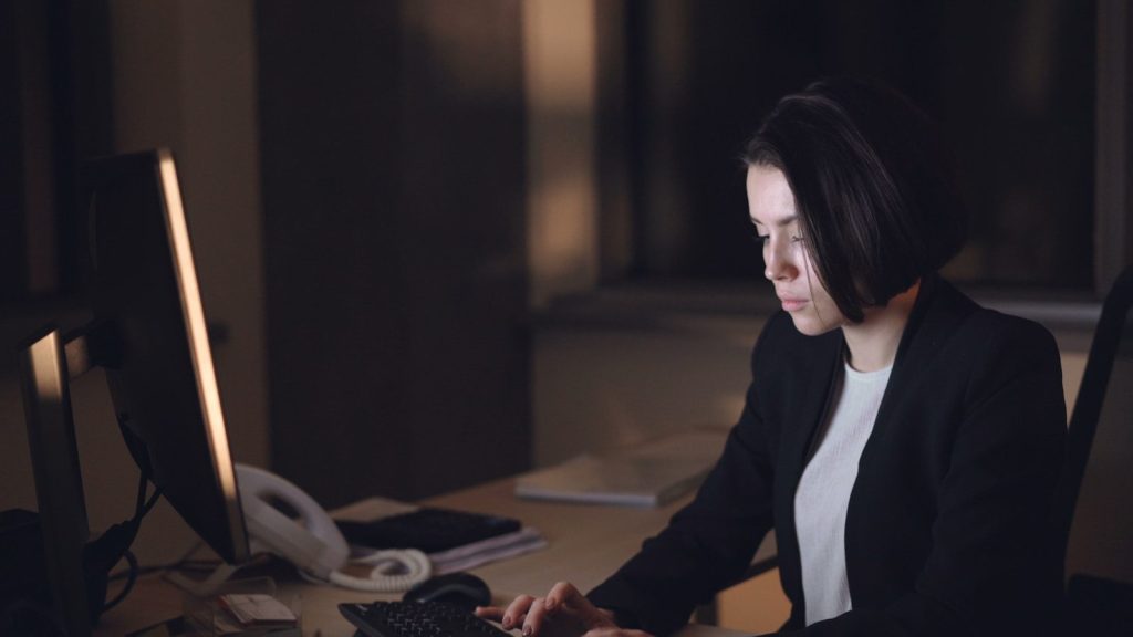 Woman working late at a computer in an office.
